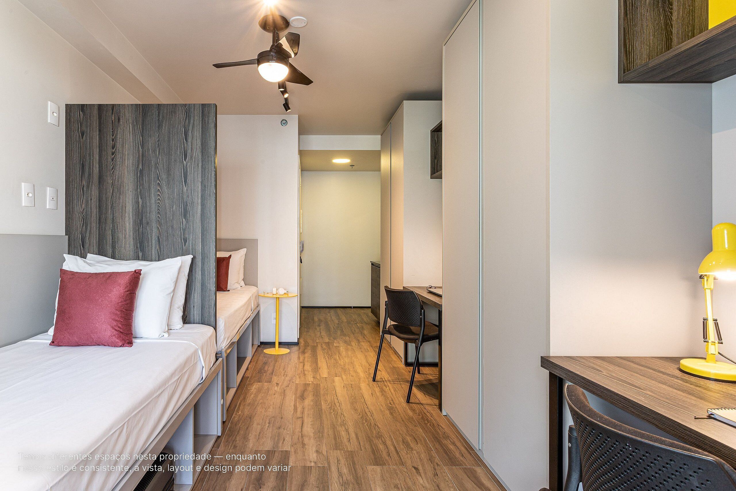A bedroom with a bed, a desk, a chair, and a ceiling fan.