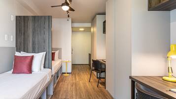 A bedroom with a bed, a desk, a chair, and a ceiling fan.