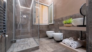 Une salle de bain moderne avec une douche à parois de verre, un lavabo, deux toilettes et un miroir.