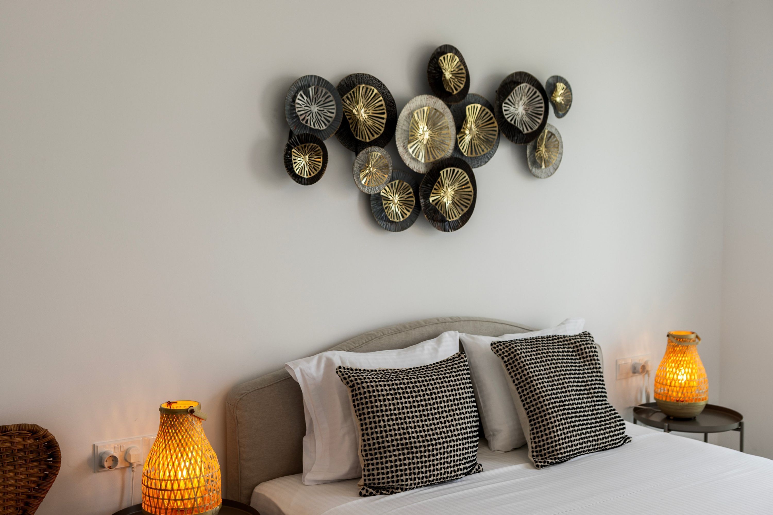 A bedroom with a bed, two bedside lamps, and wall decor.
