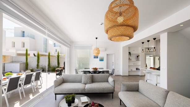 A modern living room with a sofa, coffee table, and dining area with chairs and a table. - Protaras Bay View Villa 11 (Paralimni)