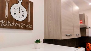 A modern kitchen with wooden cabinets, a white countertop, and a wall clock.