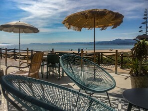 A beachside patio with wicker chairs and umbrellas, overlooking the sea and mountains. - Sea View Terrace Apartment Cullera (Cullera)