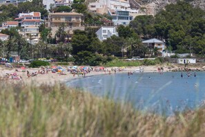 A beach with people sunbathing and swimming, surrounded by buildings and trees. - Sea View Terrace Apartment Cullera (Cullera)