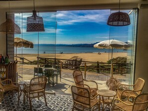 A beachside restaurant with wicker furniture and umbrellas, overlooking a beach and ocean. - Sea View Terrace Apartment Cullera (Cullera)