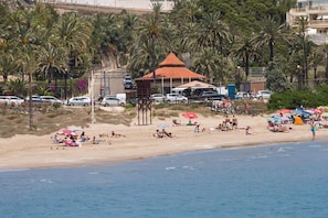 A beach with palm trees, a gazebo, and beach umbrellas. - Sea View Terrace Apartment Cullera (Cullera)