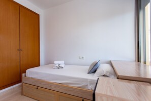 A bedroom with a wooden wardrobe, a bed with white linens, a small bedside table, and a window. - Sea View Terrace Apartment Cullera (Cullera)