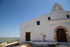 A white building with a bell tower and a cross, featuring a large wooden door and a small window. - Sea View Terrace Apartment Cullera (Cullera)