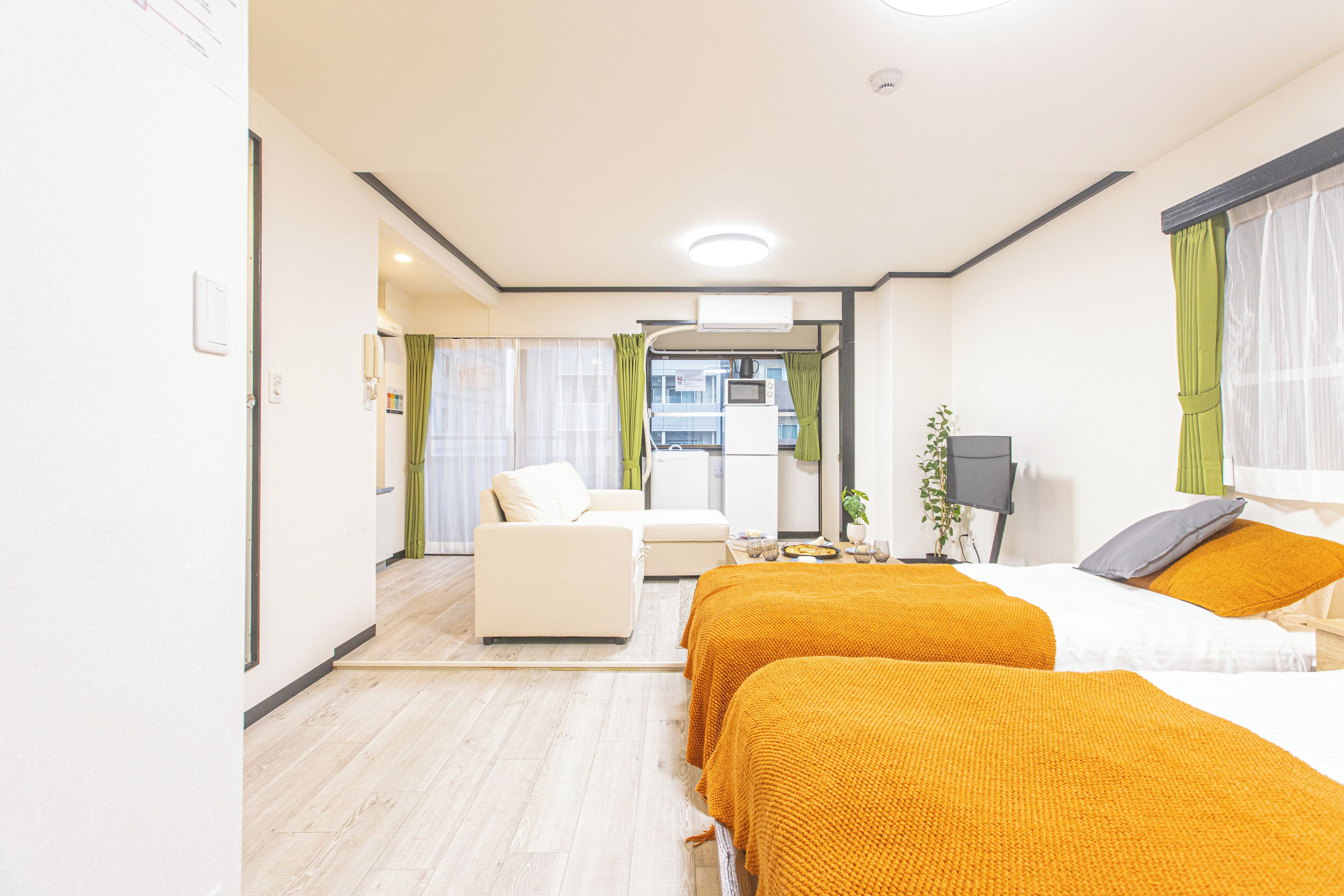A hotel room with two beds, a sofa, a desk, and a view of the city.