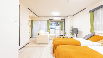 A hotel room with two beds, a sofa, a desk, and a view of the city.