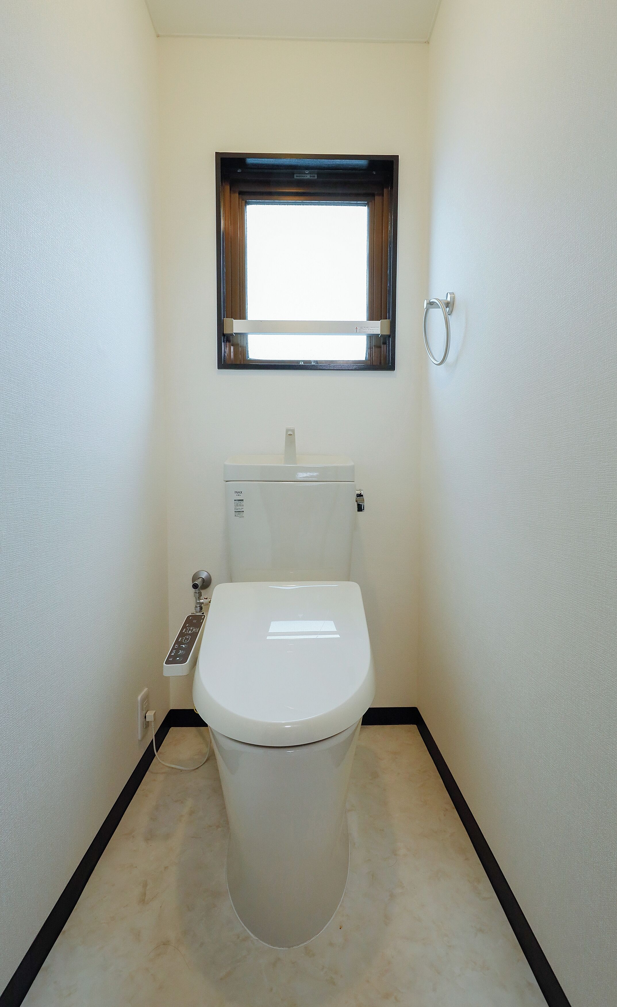 Un bagno piccolo e pulito, con il water, una finestra e un appendi asciugamani.