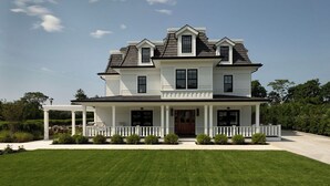 A two-story house with a front porch, a covered patio, and a well-maintained lawn. - Seven Beach Lane (Westhampton Beach)