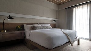 A modern bedroom with a wooden bed frame, white bedding, and two bedside lamps. - Seven Beach Lane (Westhampton Beach)