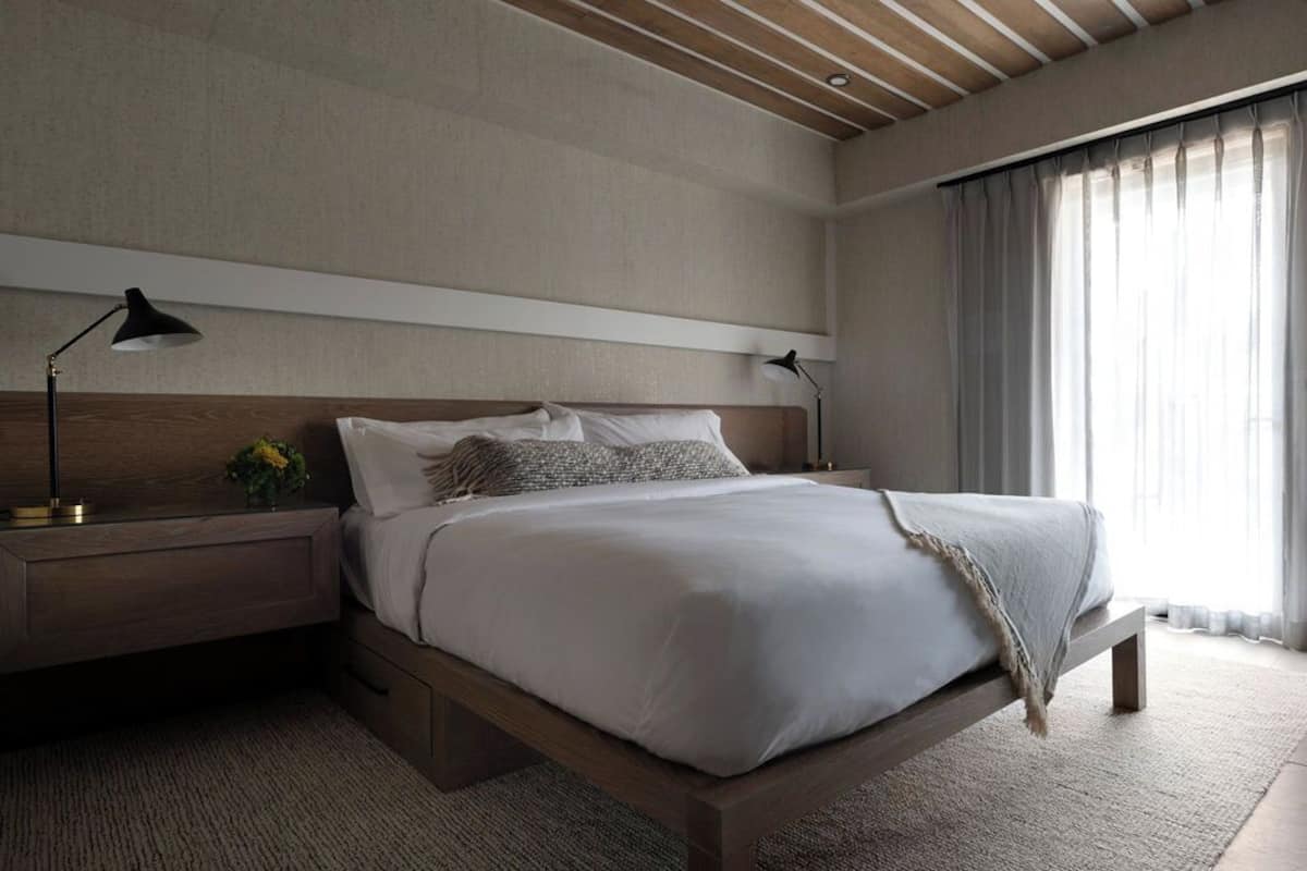 Una camera da letto moderna con un letto con struttura in legno, biancheria da letto bianca e due abat-jour.