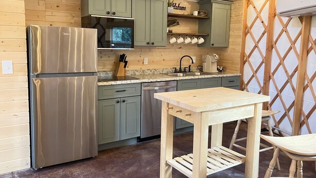 A compact kitchen with a refrigerator, microwave, sink, and wooden cabinets. - Private yurt perfect for your Magic Valley stay. (Buhl)