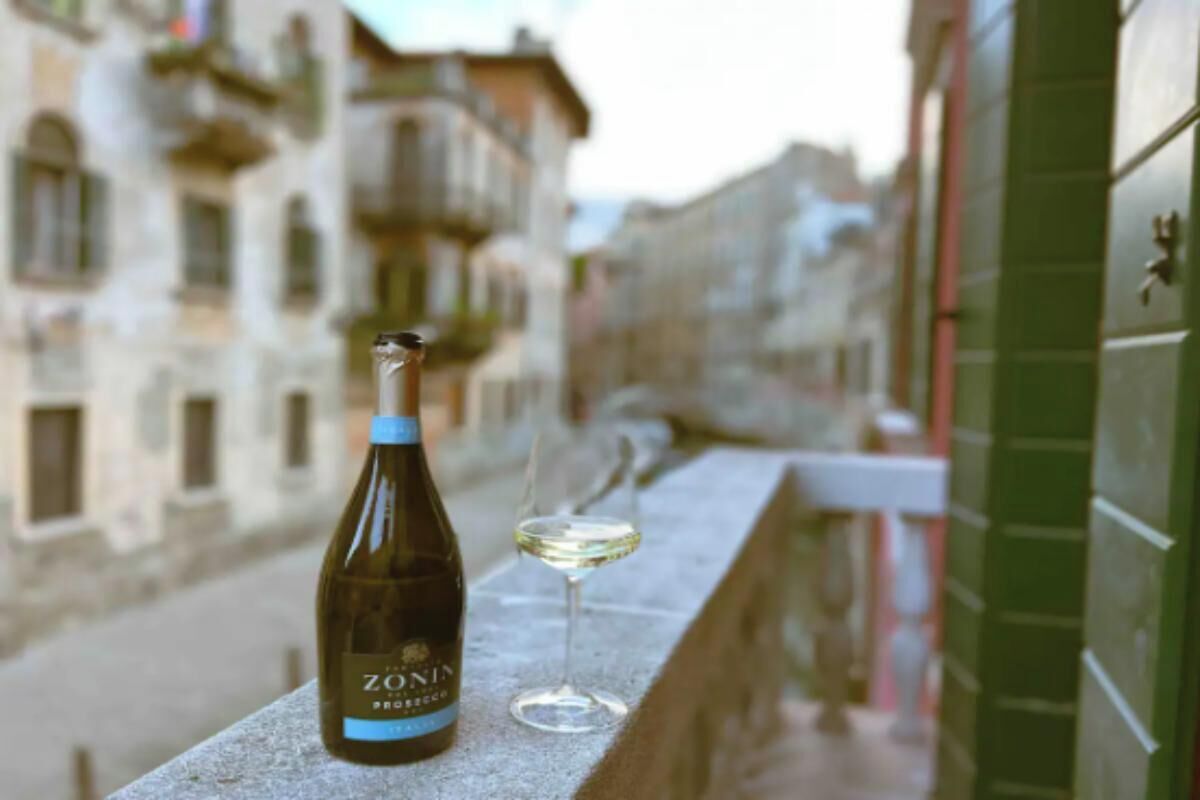 A bottle of Zonin Prosecco and a wine glass on a balcony with a view of old buildings.