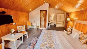 A cozy room with a bed, a desk, and a chair. There is a small table with a plant and a lamp. - Hotel Hadimba palace  (Manali)