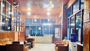 A reception area with a cash desk, reception desk, and seating area with sofas. - Hotel Hadimba palace  (Manali)