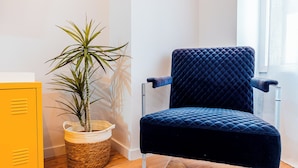 Une pièce avec un fauteuil bleu foncé à motifs matelassés, une armoire de rangement jaune et une plante en pot.