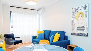Un salon moderne avec un canapé bleu, une table basse en verre et une table à manger.