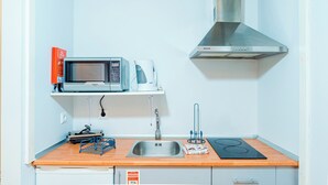 Une cuisine compacte équipée d’un four à micro-ondes, d’une machine à café et d’une hotte aspirante en acier inoxydable.