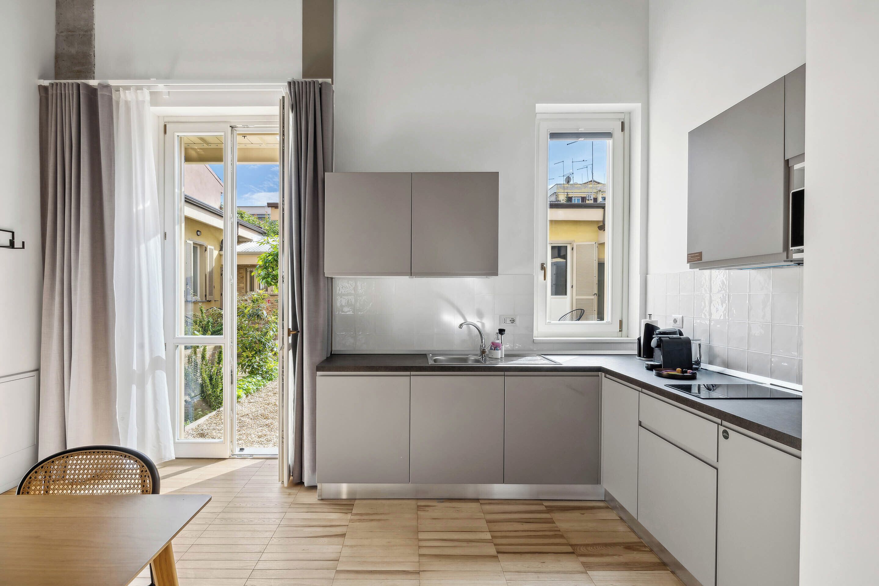 A modern kitchen with a built-in oven, a sink, and a window.