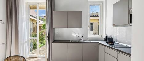 A modern kitchen with a built-in oven, a sink, and a window.