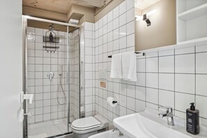 A modern bathroom with a glass-enclosed shower, a toilet, a sink, and a mirror. - Limehome Rome Via Fortebraccio (Rome)