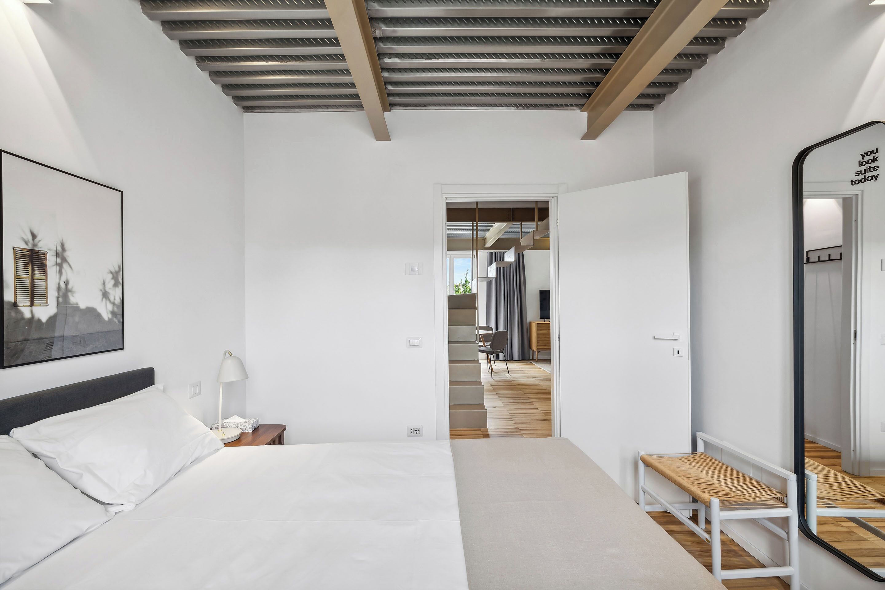 Une chambre d’hôtel moderne avec un grand lit, une table de chevet, une lampe et un miroir.