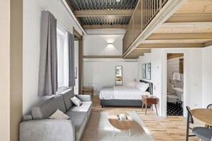 A modern bedroom with a large bed, a sofa, and a wooden coffee table. - Limehome Rome Via Fortebraccio (Rome)