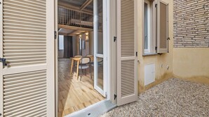Une pièce dotée d’un plancher en bois, d’un coin repas avec des chaises et une table, et d’un balcon offrant une vue.