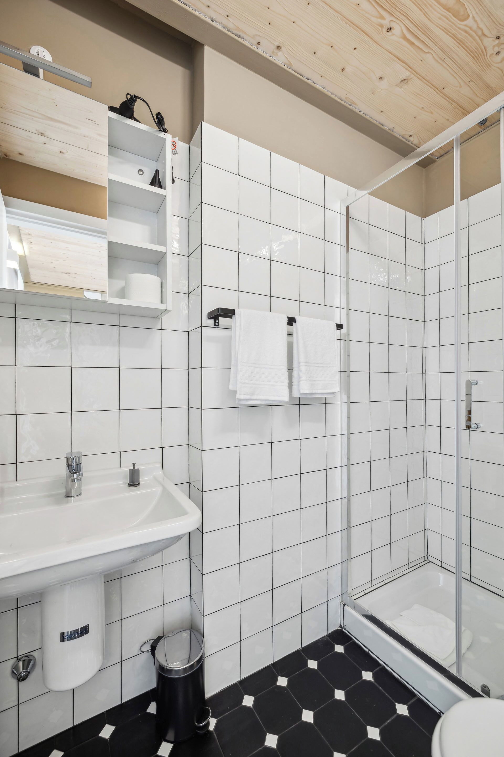 A bathroom with a white sink, a toilet, a shower, and a tiled floor.