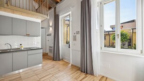 Une cuisine moderne avec des meubles gris et un plancher en bois, une fenêtre avec des rideaux gris et une vue sur l’extérieur.