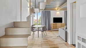 Un salon moderne avec un escalier, un coin repas, un canapé et un téléviseur.