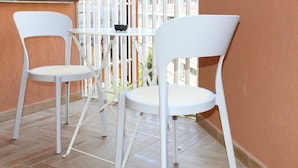 A balcony with two white chairs and a small table, overlooking a building with multiple windows. - Mama House 2 - Trastevere (Rome)