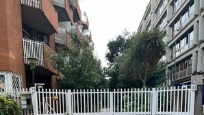 A gated entrance to a residential building with a gravel driveway and potted plants. - Mama House 2 - Trastevere (Rome)