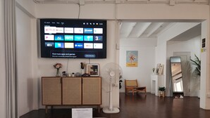A modern living room with a flat-screen TV displaying installed apps, a white coffee table with a remote control, a welcome sign, and a rattan cabinet.