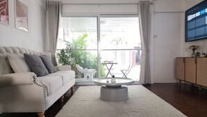 A modern living room with a sofa, a coffee table, and a TV on the wall.