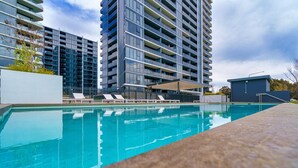 Un moderno edificio de apartamentos con piscina, balcones y una zona de estar cubierta.