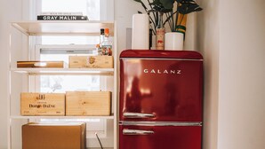 A red Galanz refrigerator next to a white cabinet with wooden boxes and a plant on top. - Petite Maison: Hip & Historic (Telluride)