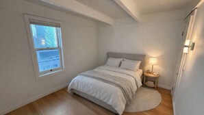 A bedroom with a bed, a nightstand, a lamp, and a window. - Petite Maison: Hip & Historic (Telluride)