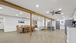 Une cuisine spacieuse avec des poutres en bois, un coin repas avec des chaises et un réfrigérateur.