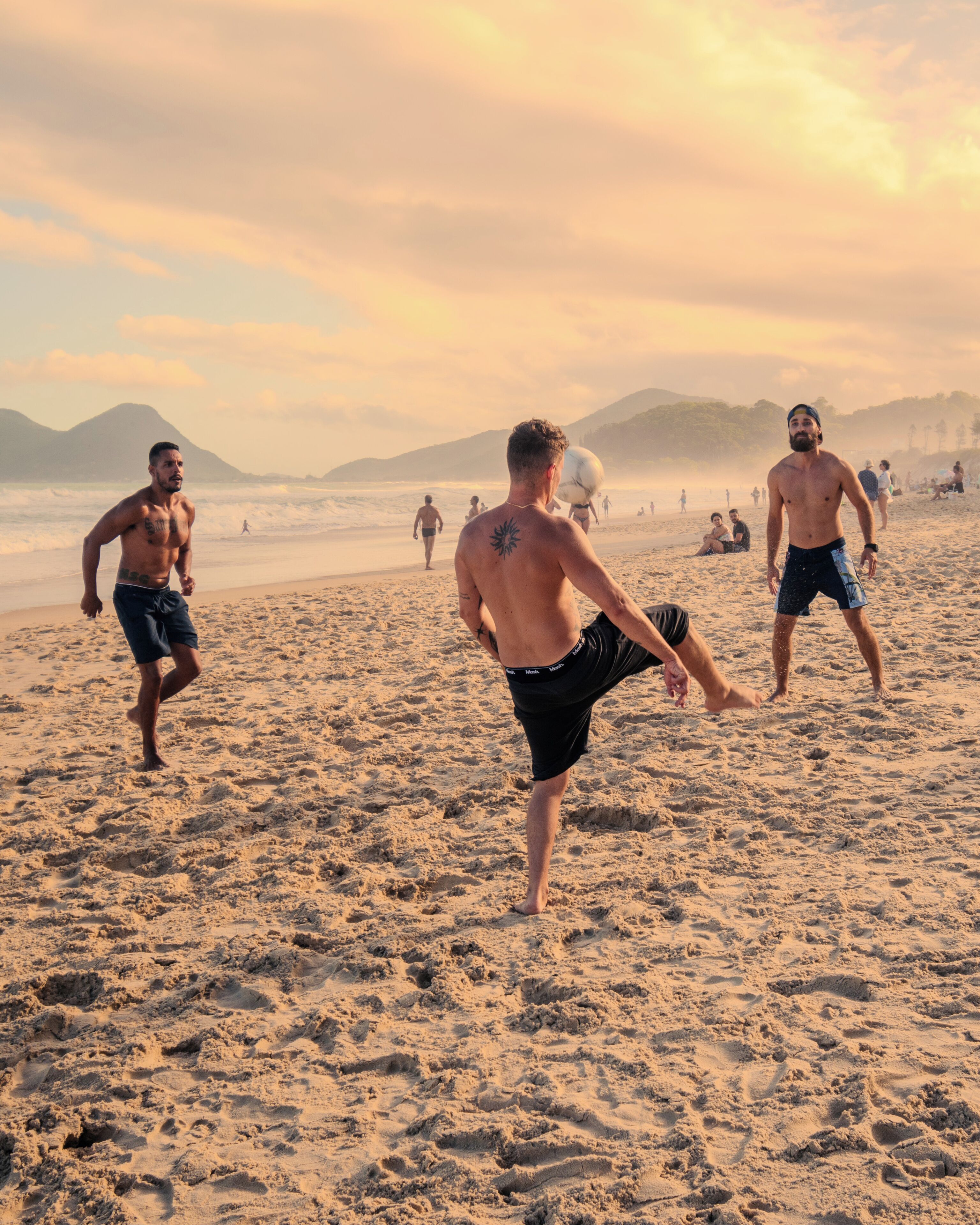 Cena de praia com pessoas caminhando e brincando.