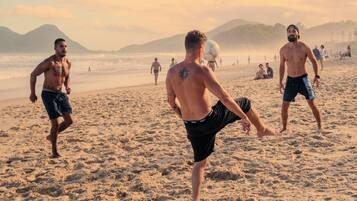 Cena de praia com pessoas caminhando e brincando.