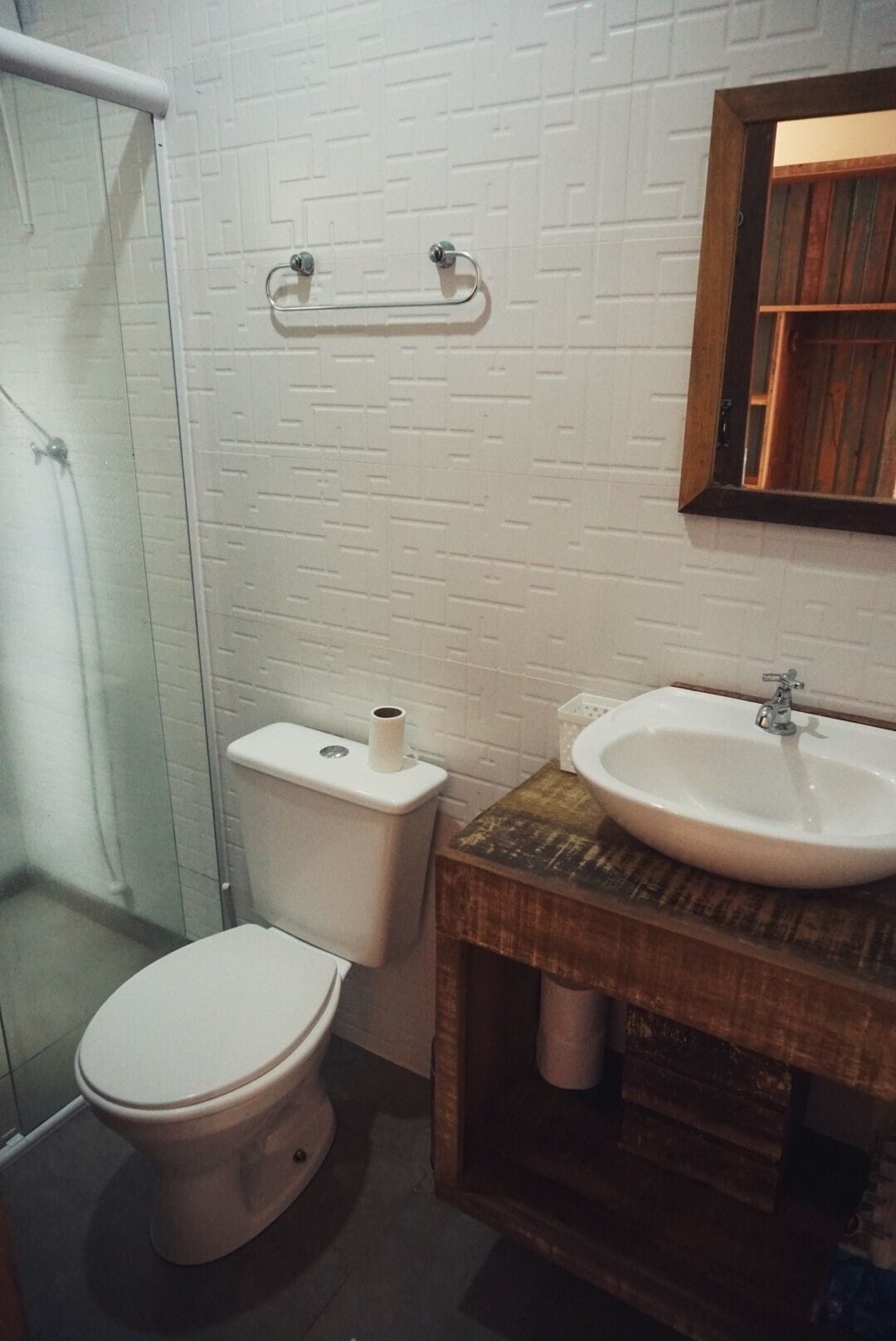 A bathroom with a white toilet, a sink, and a shower area.