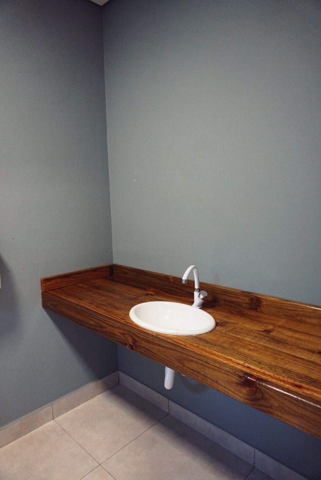 Une salle de bain avec un meuble-lavabo en bois, un lavabo blanc et un mur bleu.