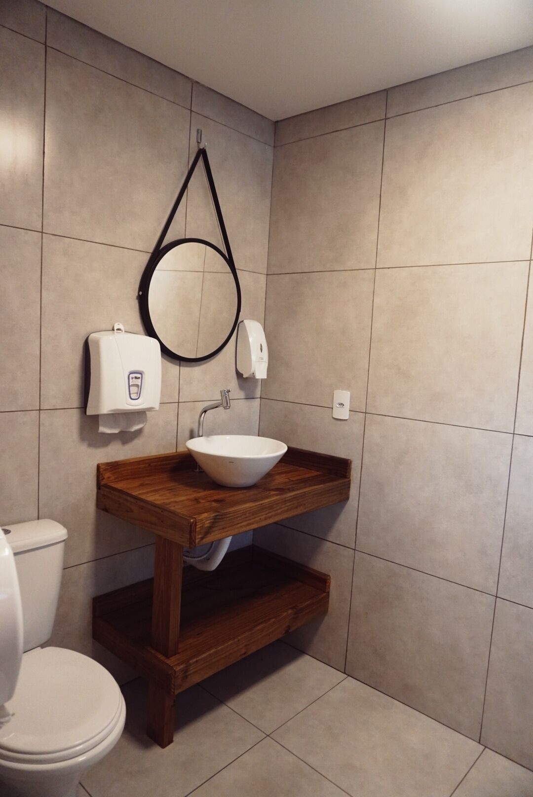 A bathroom with a wooden vanity, a white sink, a mirror, and a toilet.