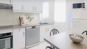 A modern kitchen with white cabinets, a dishwasher, a microwave, and a sink.
