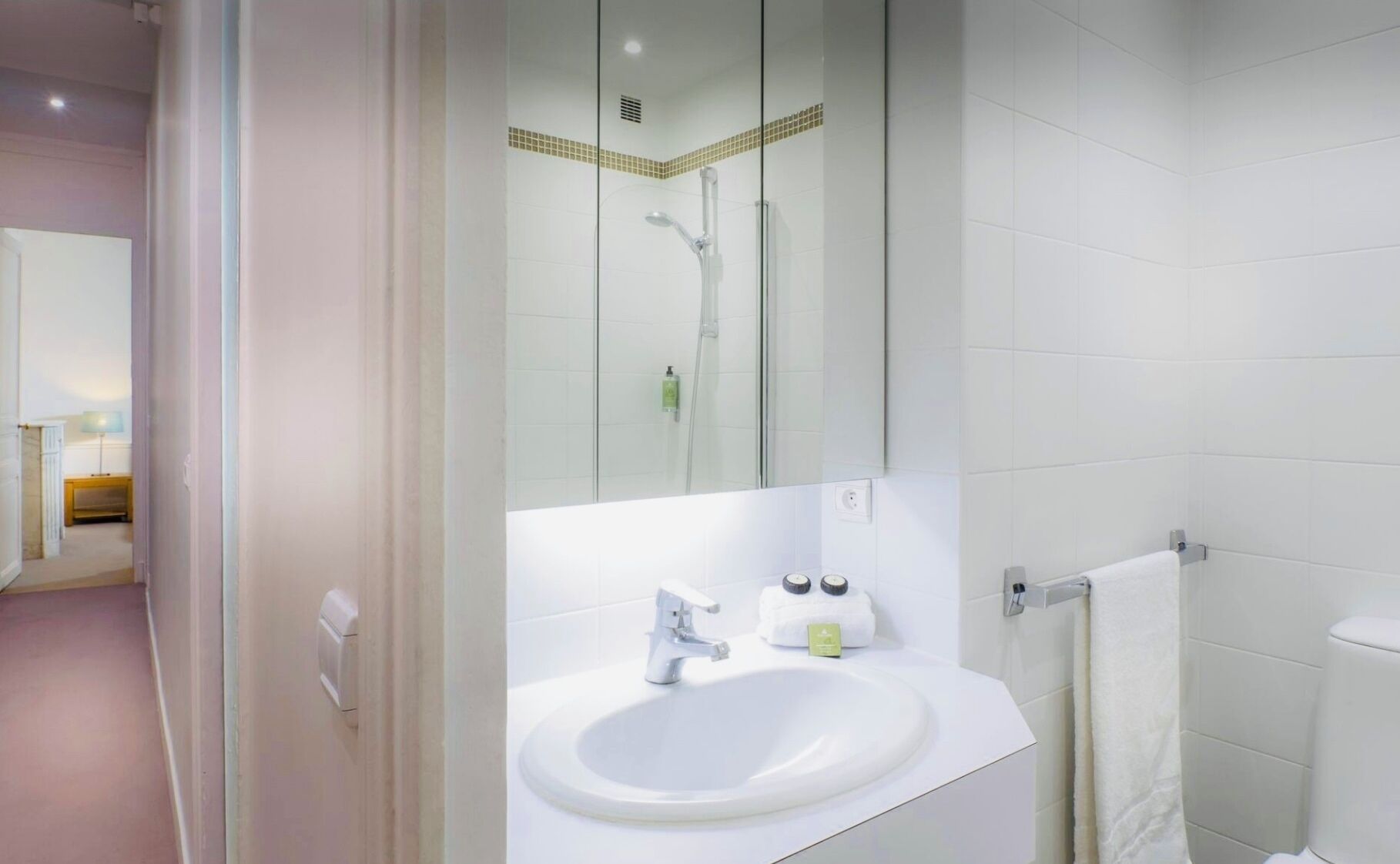 A modern bathroom with a white sink, a mirror, and a shower.