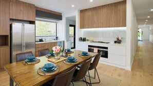 Eine moderne Küche mit Holzausstattung, einem Edelstahlkühlschrank und einem Essbereich mit einem Holztisch, gedeckt für vier Personen.